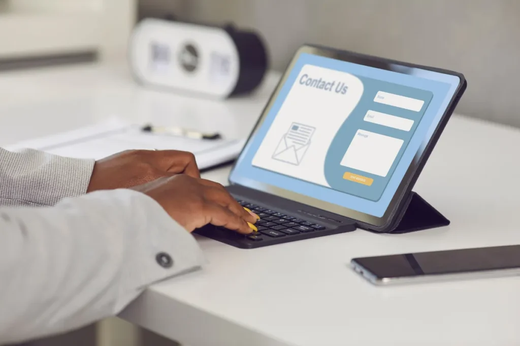 Pessoa digitando em tablet com formulário de contato de landing page aberto, com campos de nome, email e mensagem visíveis
